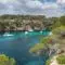 Boats are docked in a Mallorca paradise surrounded by blue Mediterranean water and trees.