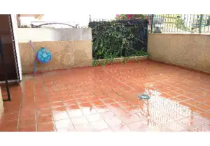 A 76m2 + 37m2, two-bedroom apartment in Malaga-FUENGIROLA with a patio featuring a red tiled floor and fence.