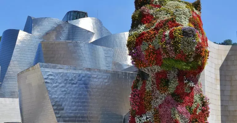 A flower dog in front of a building located in Bilbao mercado.