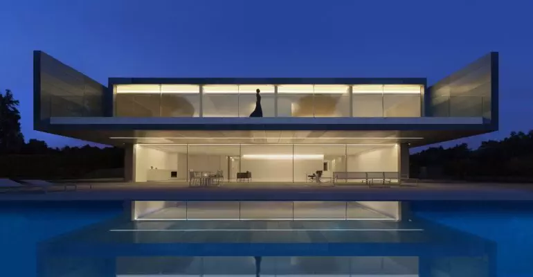 A modern house with a swimming pool at night.