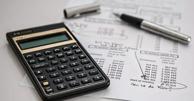 A calculator sits on top of a piece of paper calculating Spanish property tax.