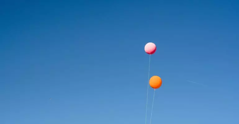 A group of Spanish property experts flying kites in a blue sky.