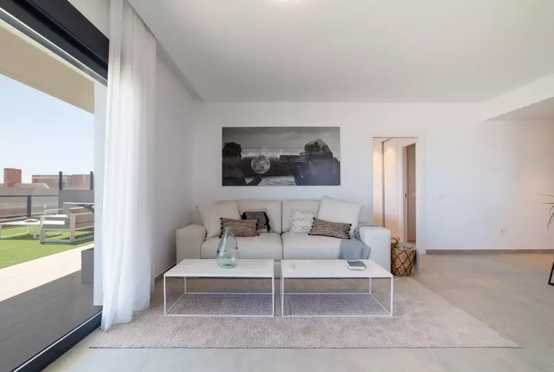 A cheap living room with a white couch and a sliding glass door.