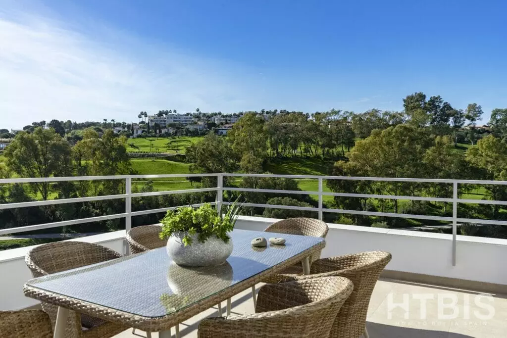 A balcony with a table and chairs overlooking the Estepona Golf Course.