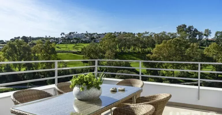 A balcony with a table and chairs overlooking the Estepona Golf Course.