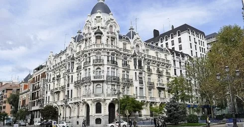 An ornate building, appealing to real estate foreign investors, sits on the corner of a street.