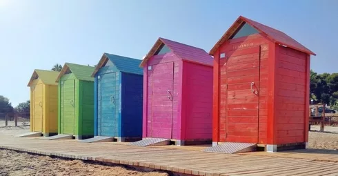 Colorful beach huts for sale on a wooden boardwalk.