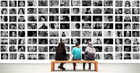 Two foreigners living in Spain sitting on a bench in front of a wall of black and white photos.