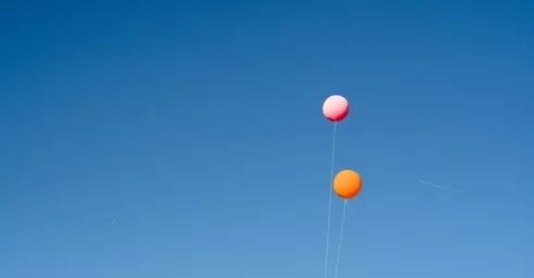 A group of Spanish property experts flying kites in a blue sky.