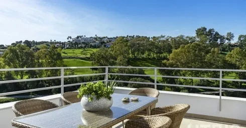 A balcony with a table and chairs overlooking the Estepona Golf Course.